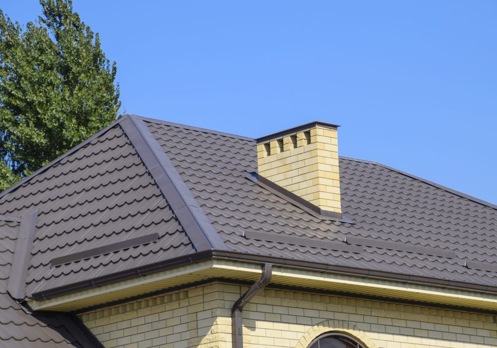 Brown corrugated metal profile roof. Chimney and ventilation of yellow brick